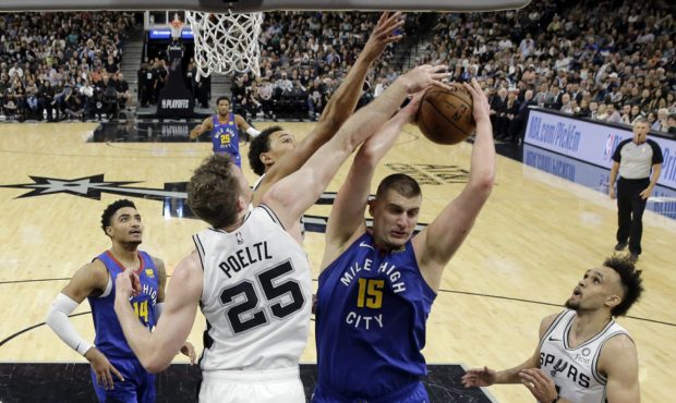 Denver Nuggets center Nikola Jokic (15) is defended by San Antonio Spurs center Jakob Poeltl (25) a...