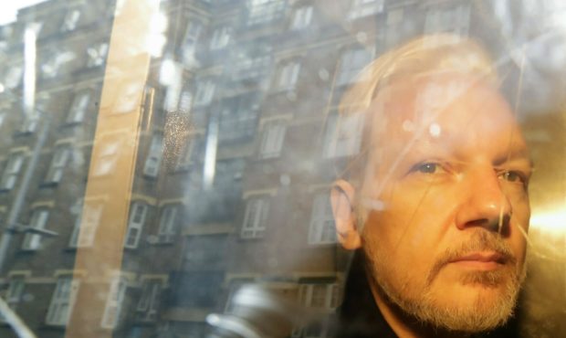 FILE - In this Wednesday May 1, 2019 file photo, buildings are reflected in the window as WikiLeaks...