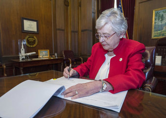 This photograph released by the state shows Alabama Gov. Kay Ivey signing a bill that virtually out...