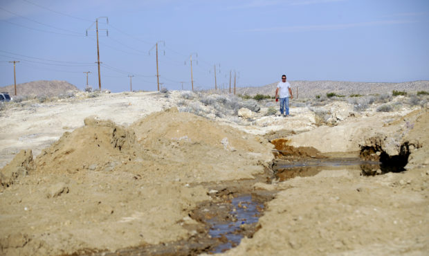 Water from a broken line runs down a crack on the ground in the aftermath of an earthquake along hi...