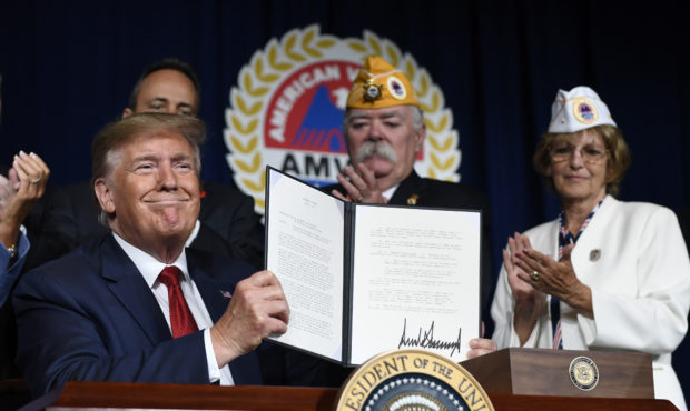 President Donald Trump holds up a presidential memorandum that he signed that discharges the federa...