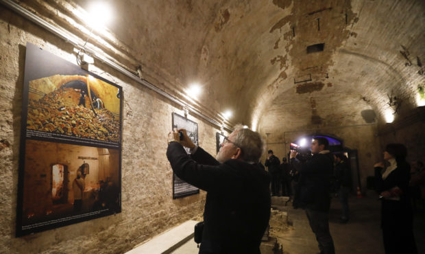 People cover historic photos as they wait to see an escape tunnel, underneath the Berlin Wall which...