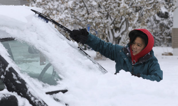 Meg Jones cleans the snow off her car outside her house on 2nd Avenue in Scottsbluff, Neb., Tuesday...