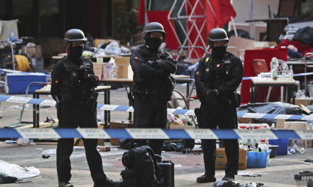 Bomb disposal police watch from a cordoned area as evidence is collected in a cordoned off area in ...