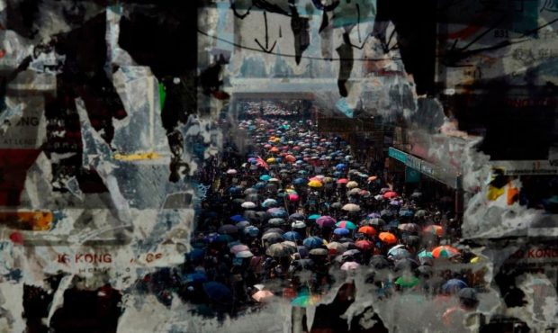 Marching anti-government protesters are seen through a window with peeled-off posters on October 1....