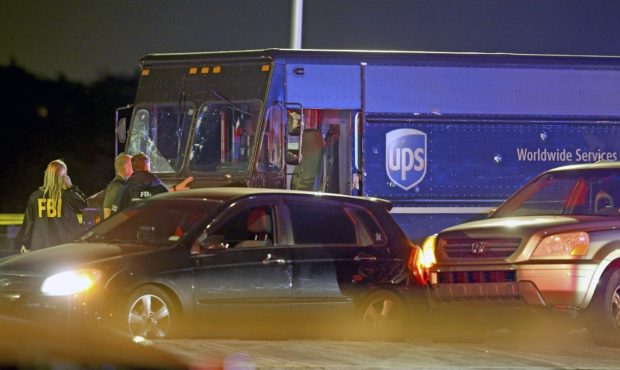 Law enforcement stand near a vehicle that appears to be part of the crime scene where four people w...