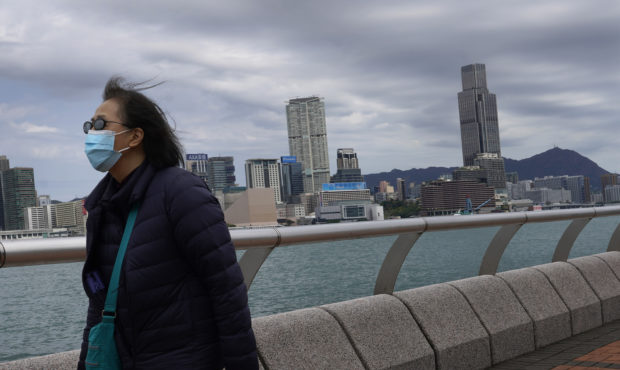 A woman wearing a face mask walks at the waterfront against the Victoria Habour in Hong Kong Sunday...