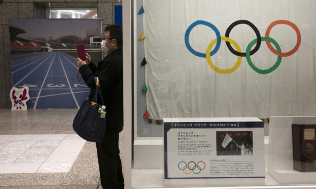 FILE - In this Feb. 18, 2020, file photo, a man wearing a mask takes pictures of the mascots for th...