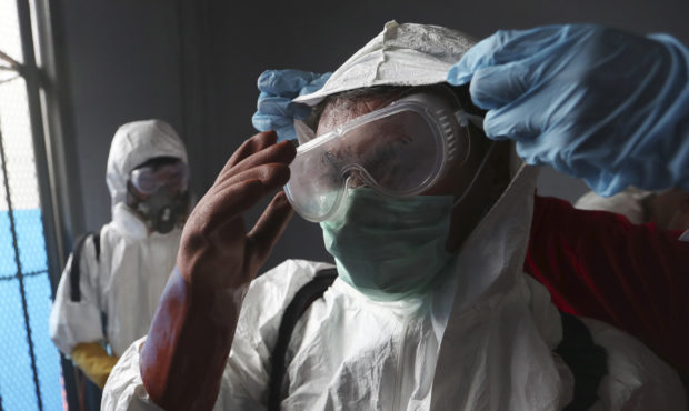 A member of Indonesian Red Cross receives assistance from a colleague to adjust his protective suit...