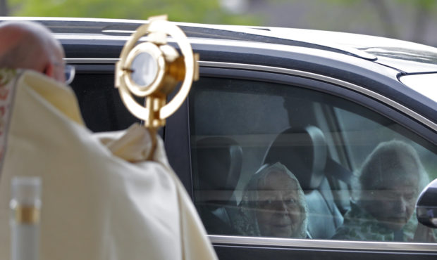 FILE -- Parishioners pray from their car as Fr. Steve Buno, Pastor of St. Rita of Cascia Catholic C...