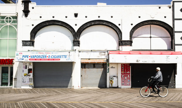 A cyclist rides past shuttered businesses during the coronavirus outbreak on the boardwalk in Atlan...