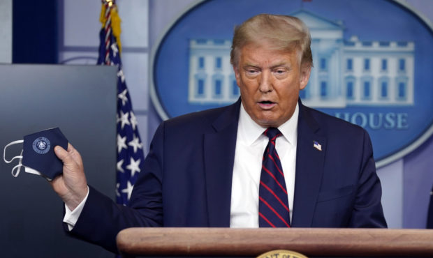 President Donald Trump holds a face mask as he speaks during a news conference at the White House, ...