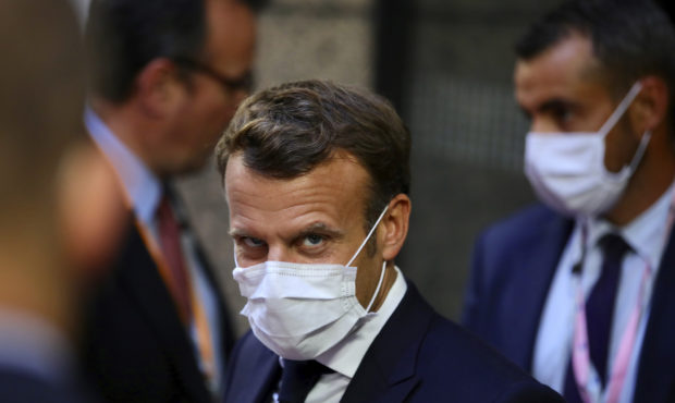 French President Emmanuel Macron, center, leaves the European Council building in the early morning...