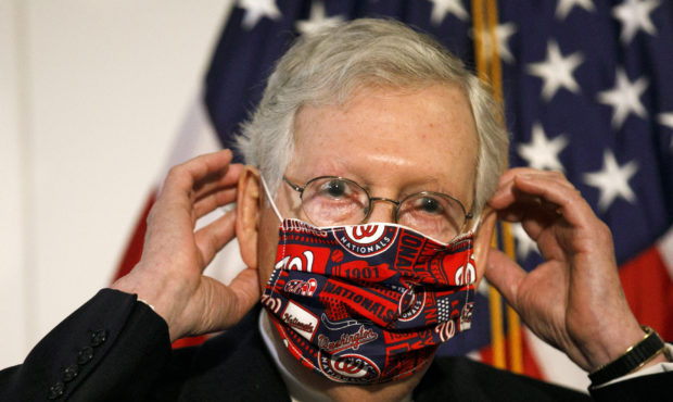 Senate Majority Leader Mitch McConnell of Ky., replaces his face mask after speaking at news confer...