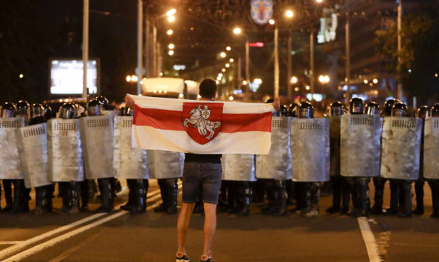 A protester holds an old Belarusian national flag as he stands in front of police line during a ral...