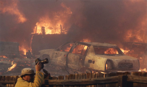 FILE - In this Dec. 5, 2017, file photo, a news photographer takes pictures of a wildfire in the La...