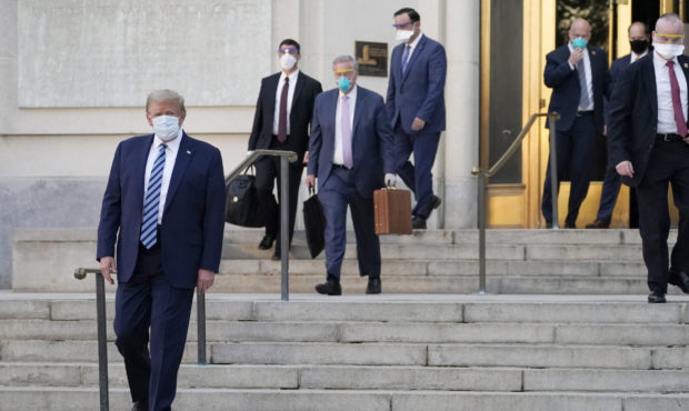 President Donald Trump, left, walks out of Walter Reed National Military Medical Center to return t...