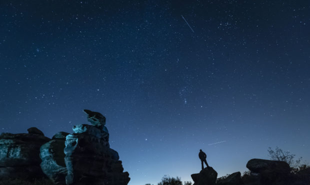 EDITORS NOTE: PHOTO TAKEN WITH SLOW SHUTTER SPEED A plane and a Satellite pass by as a man stargaze...