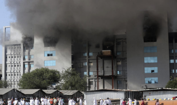 Employees leave as smoke rises from a fire at Serum Institute of India, the world's largest vaccine...