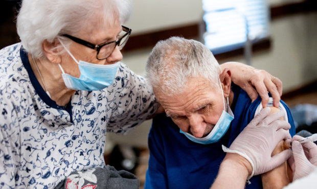 Lois Larsen, 83, comforts her husband, Jerry, 86, while he receives his second dose of the Pfizer-B...