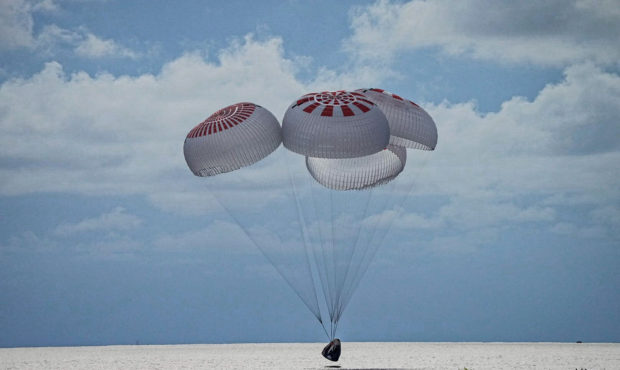 In this image taken provided by SpaceX, a capsule carrying four people parachutes into the Atlantic...
