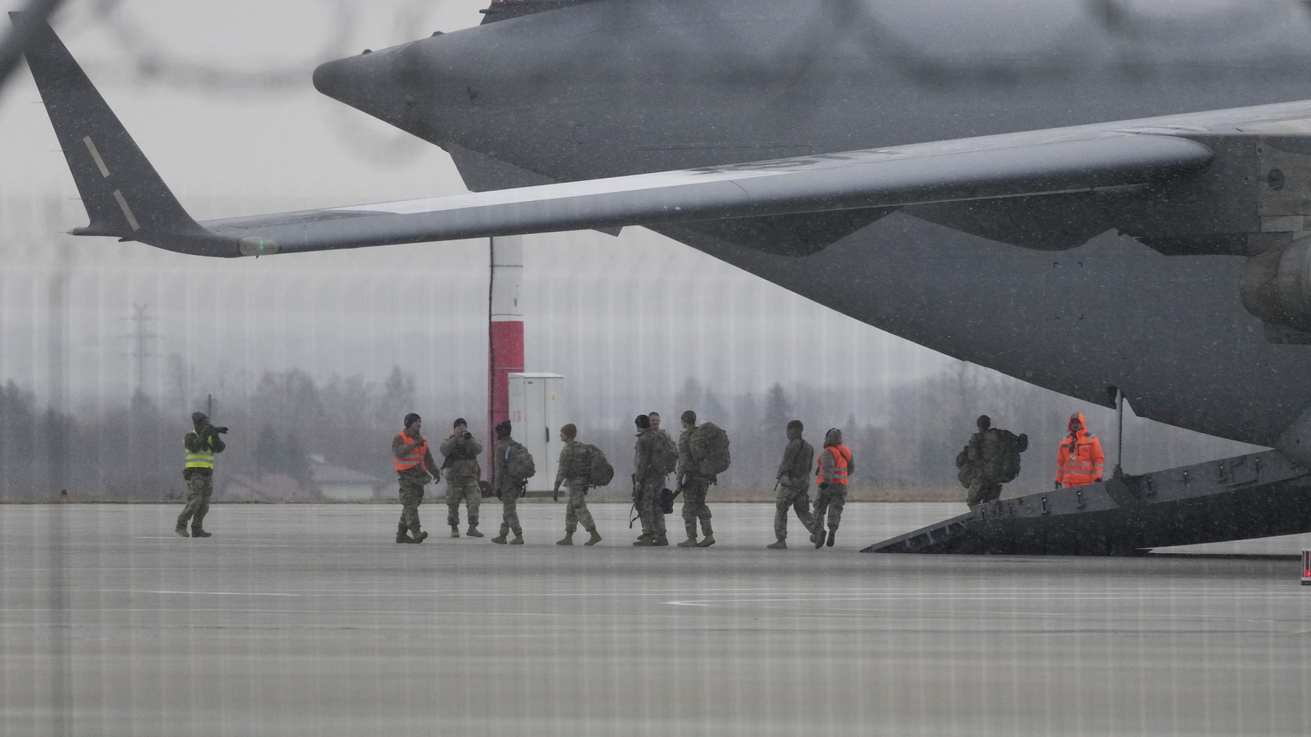 U.S. Army troops of the 82nd Airborne Division unloading vehicles from a transport plane after arri...