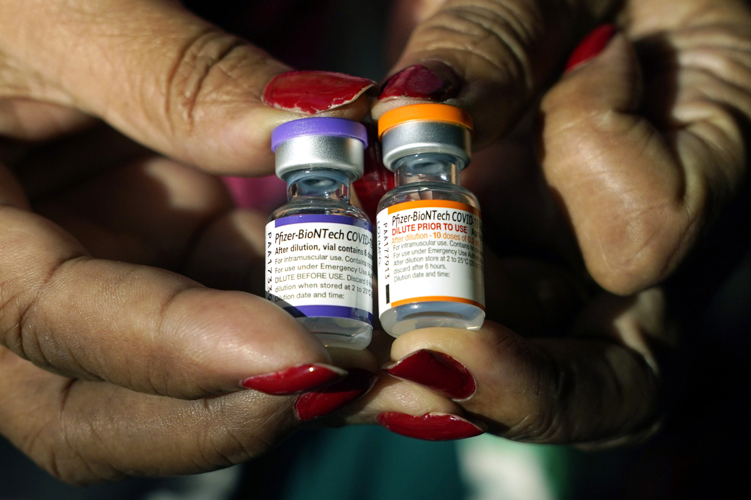 Hands holding two small viles of vaccine....