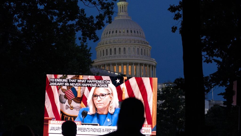 People gather in a park outside of the U.S. Capitol to watch the Jan. 6 House committee investigati...