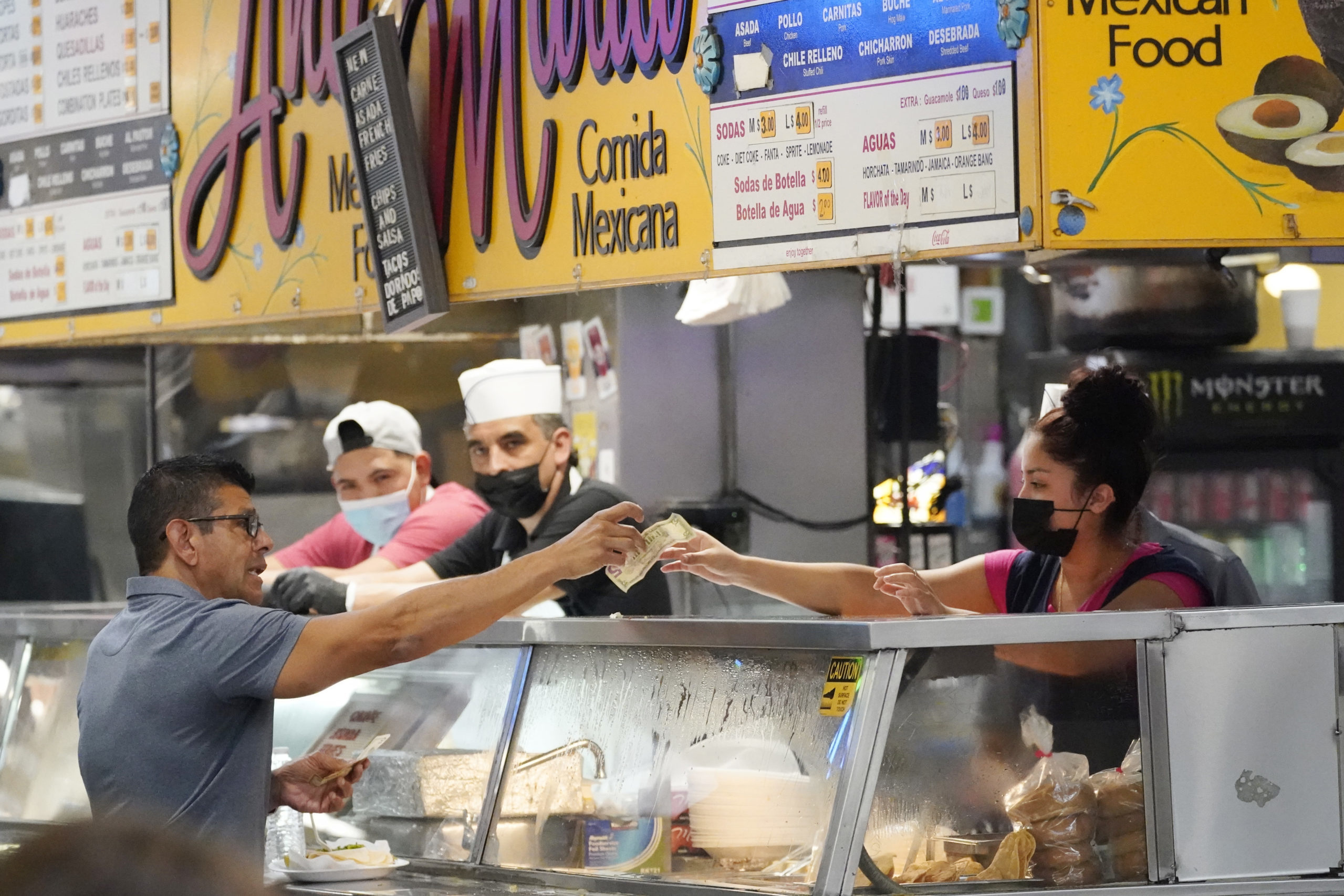 Money is exchanged at a food stand while workers wear face masks inside Grand Central Market on Wed...