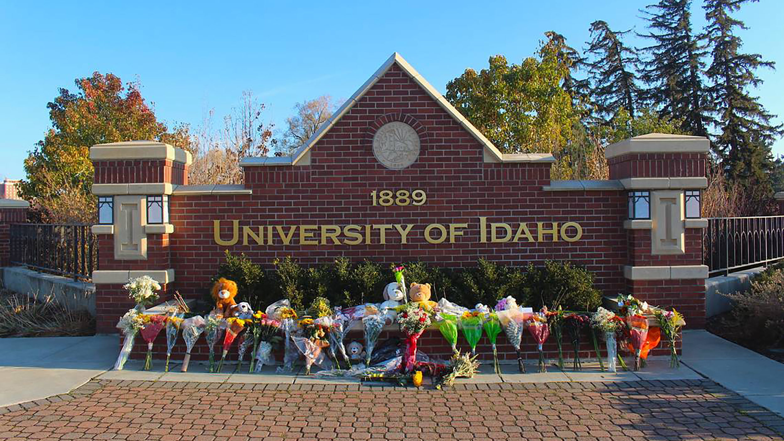 Flowers and stuffed animals are lined up outside a sign along Pullman Road in Moscow, Idaho, to pay...