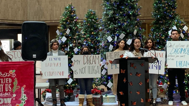 People stand with signs supporting DACA recipients during a press conference...