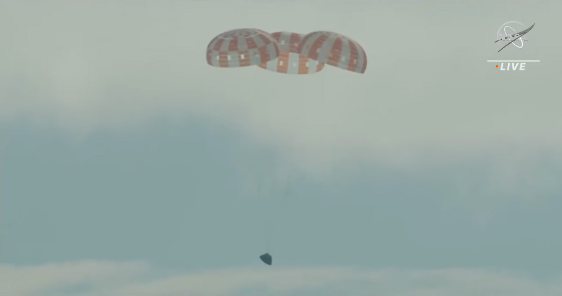 The Orion capsule, with its three main parachutes deployed, approaches the surface of the ocean. (N...