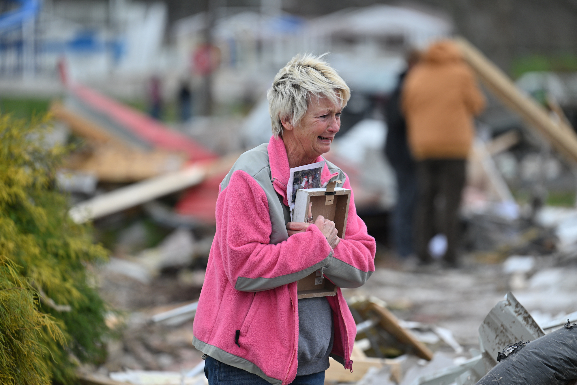 Debbie Lowdermilk holds photographs as she reacts while looking at the destroyed school she owns th...