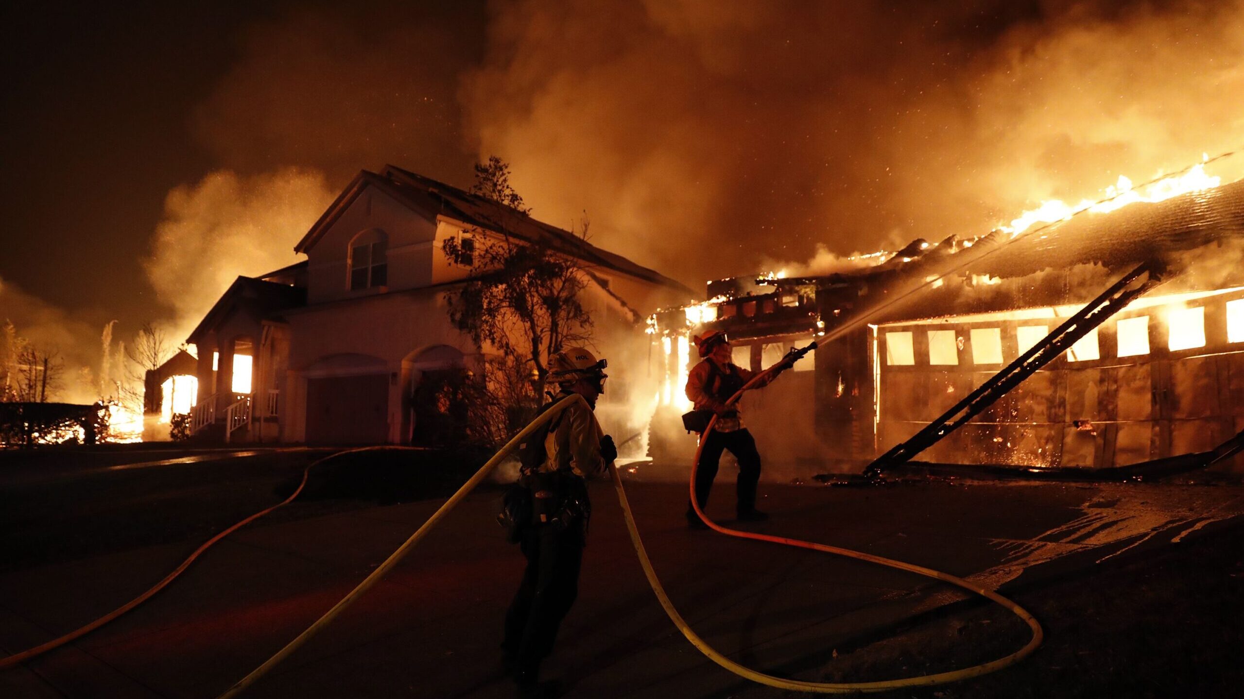 Firefighters try to keep house fires from spreading on Mountain Hawk Drive as the Shady Fire burns ...
