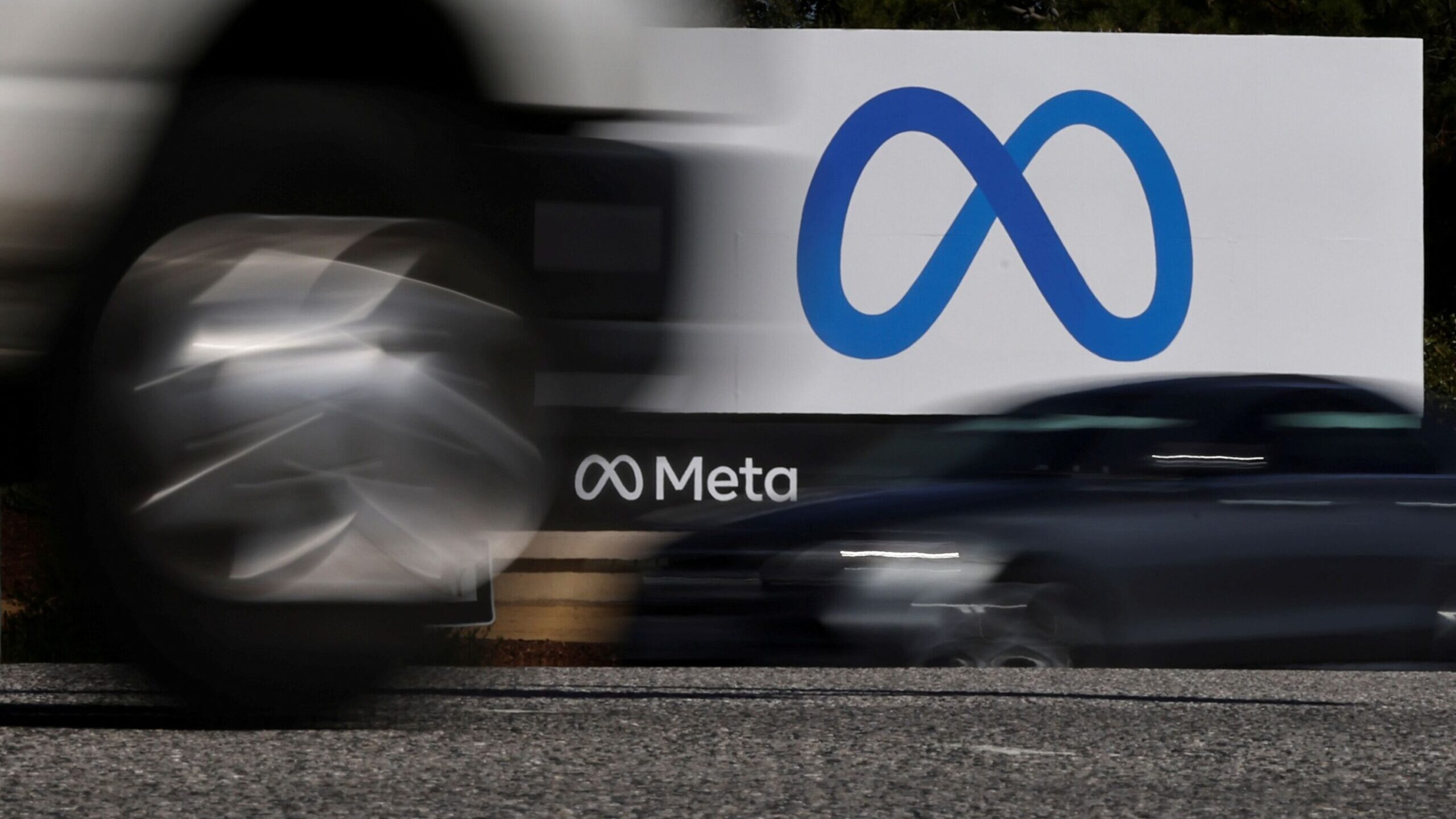 Cars drive past a sign of Meta, the new name for the company formerly known as Facebook, at its hea...