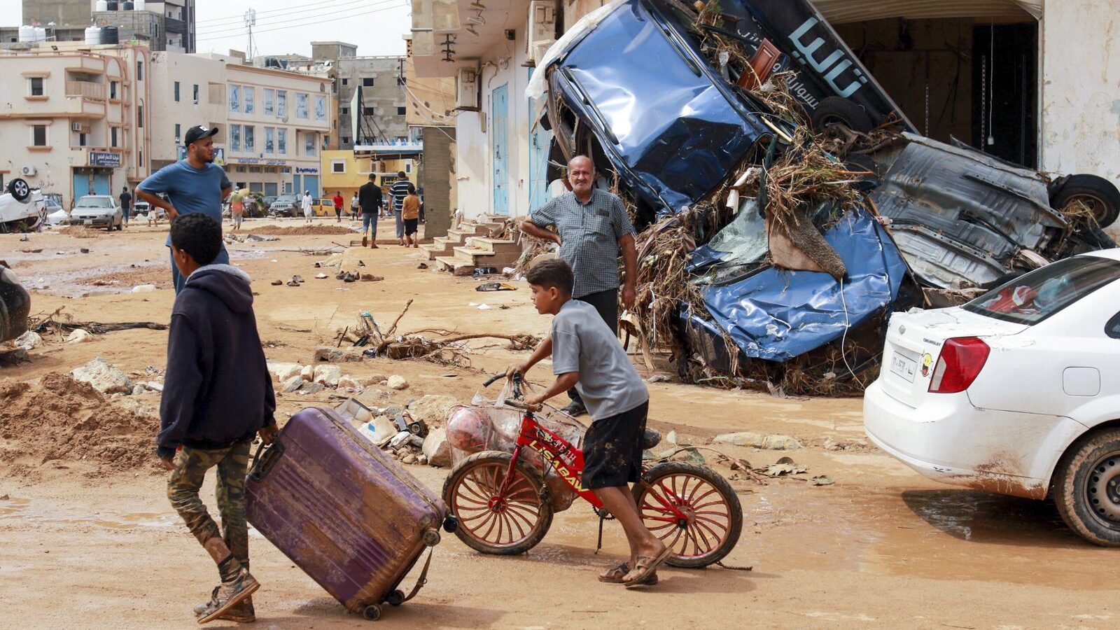 A boy pulls a suitcase past debris in a flash-flood damaged area in Derna, eastern Libya, on Sept. ...