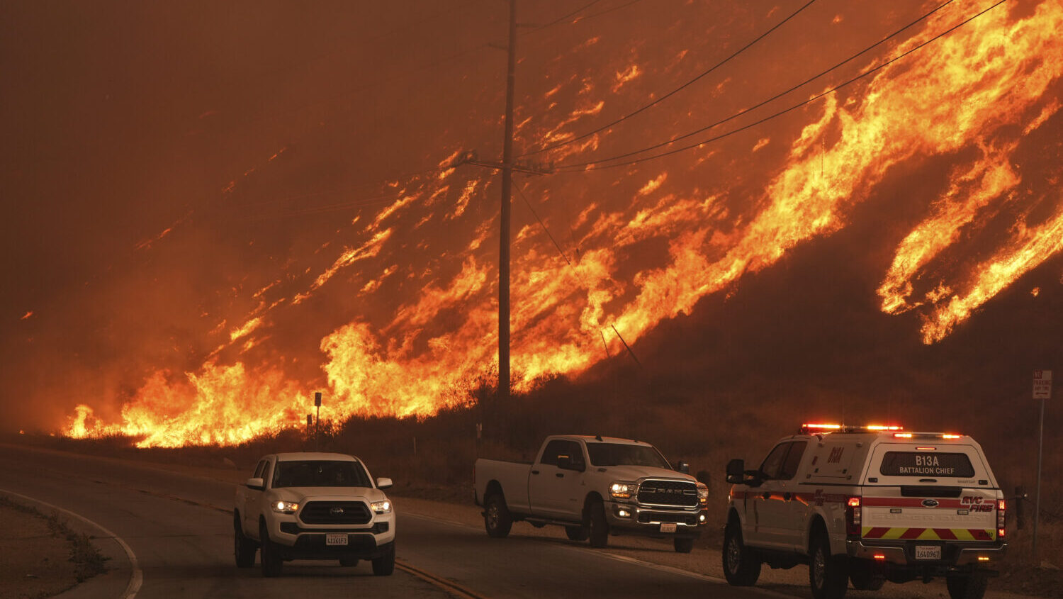 firefighters monitor flames caused by the Hughes Fire along Castaic Lake in Castaic, Calif., Wednes...