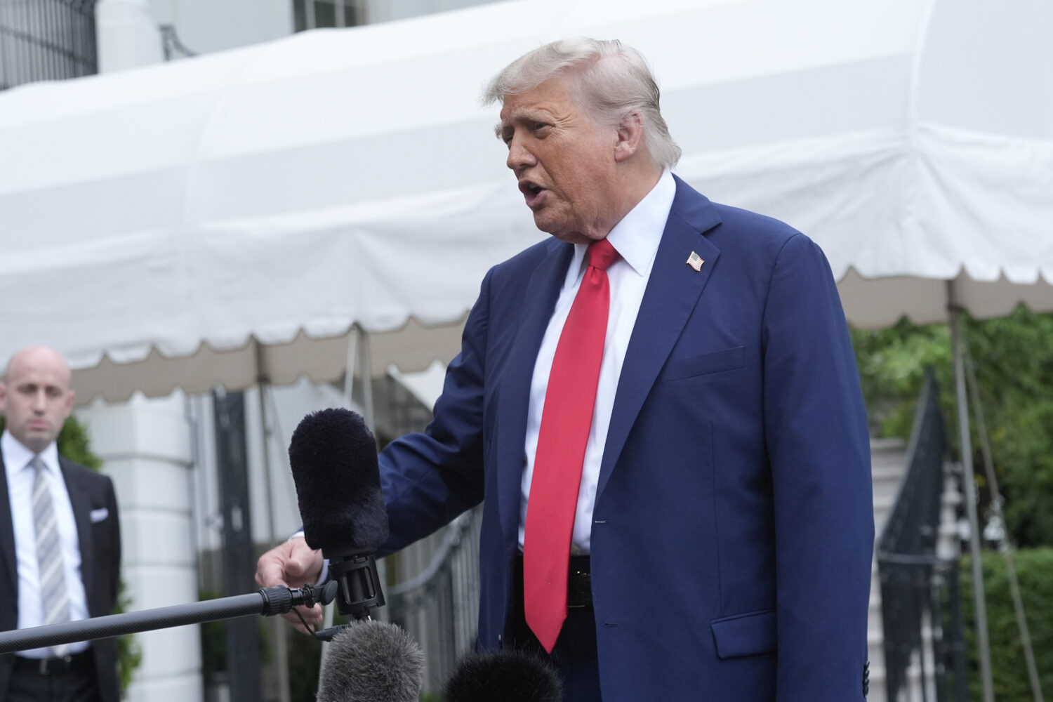 President Donald Trump speaks with reporters as White House Deputy Chief of Staff Stephen Miller li...