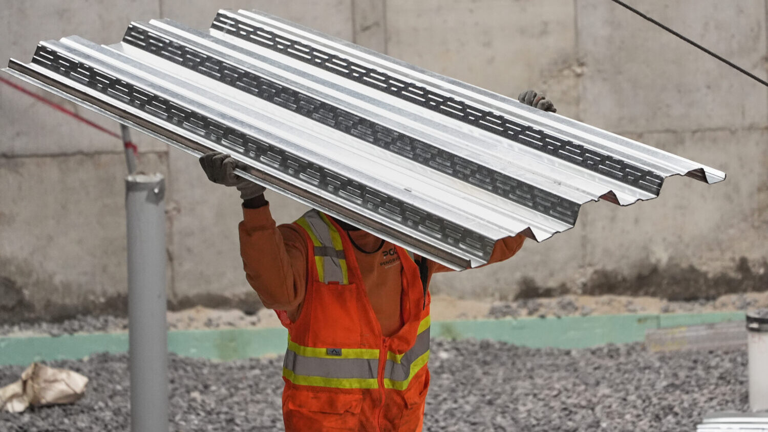 FILE - A construction worker carries steel decking at the site of a construction of a housing proje...