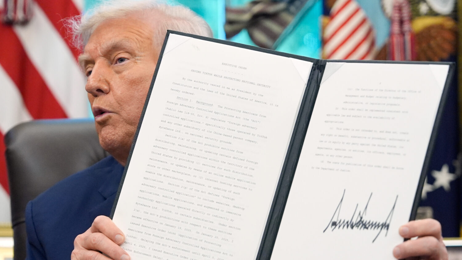 President Donald Trump holds a signed executive order regarding TikTok in the Oval Office at the Wh...
