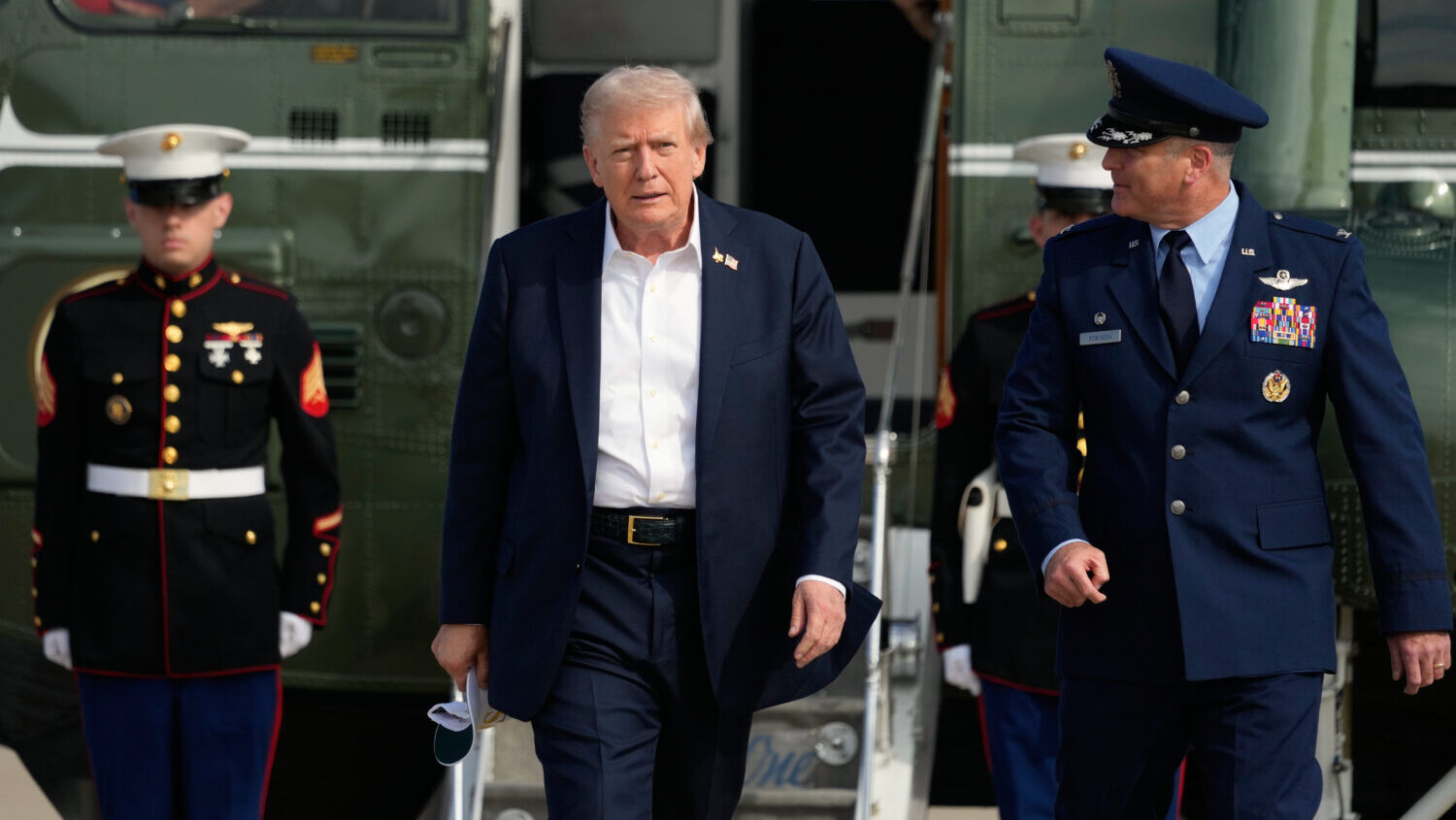 President Donald Trump, center, is escorted by Air Force Col. Christopher M. Robinson, commander of...
