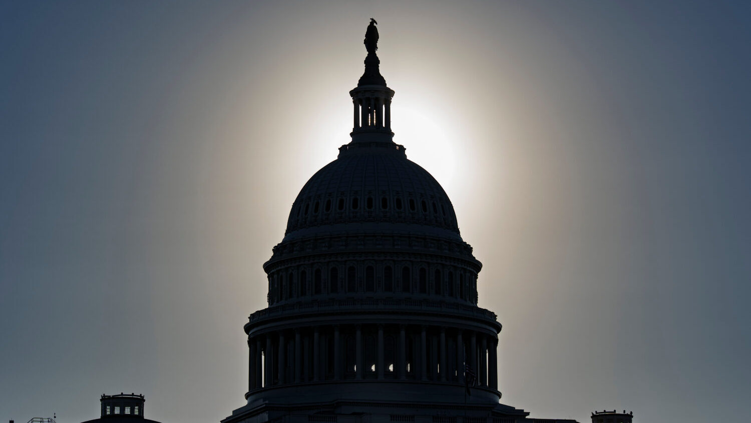 The U.S. Capitol is silhouetted by the stark glare of the morning sun as a government shutdown begi...
