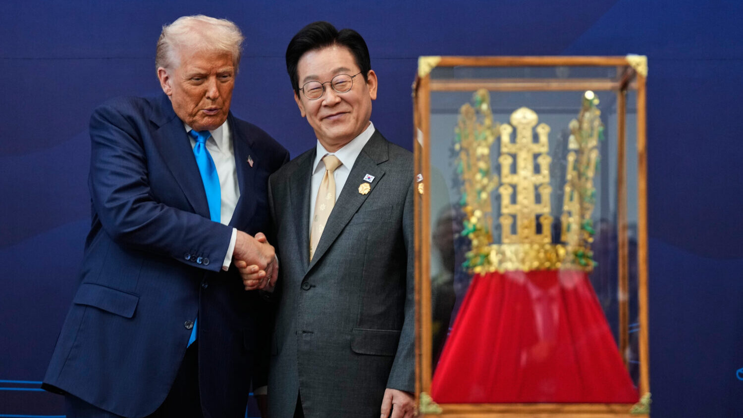President Donald Trump shakes hands with South Korean President Lee Jae Myung as he receives a gift...