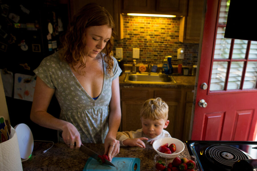 Taylor Moyer slices strawberries as her youngest son, Bradley, helps put the sliced fruit into a bo...