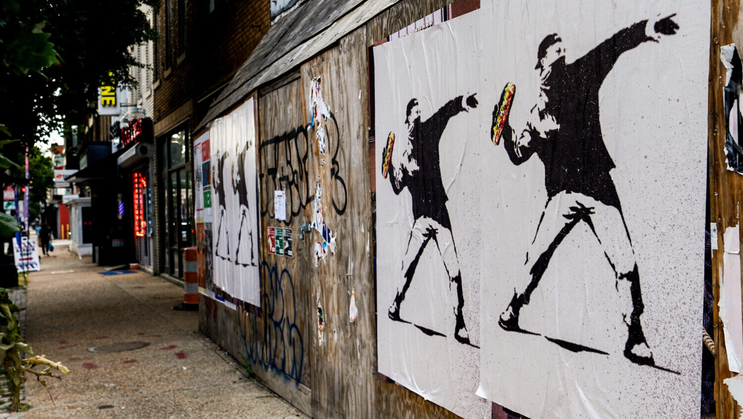 Posters of a person throwing a sandwich are pictured along H Street, Aug. 17, 2025, in Washington. ...