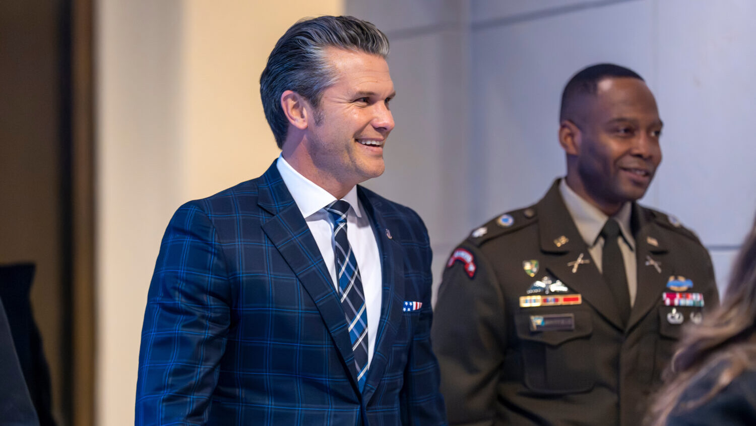 Defense Secretary Pete Hegseth smiles as he walks to a secure room in the basement of the Capitol t...
