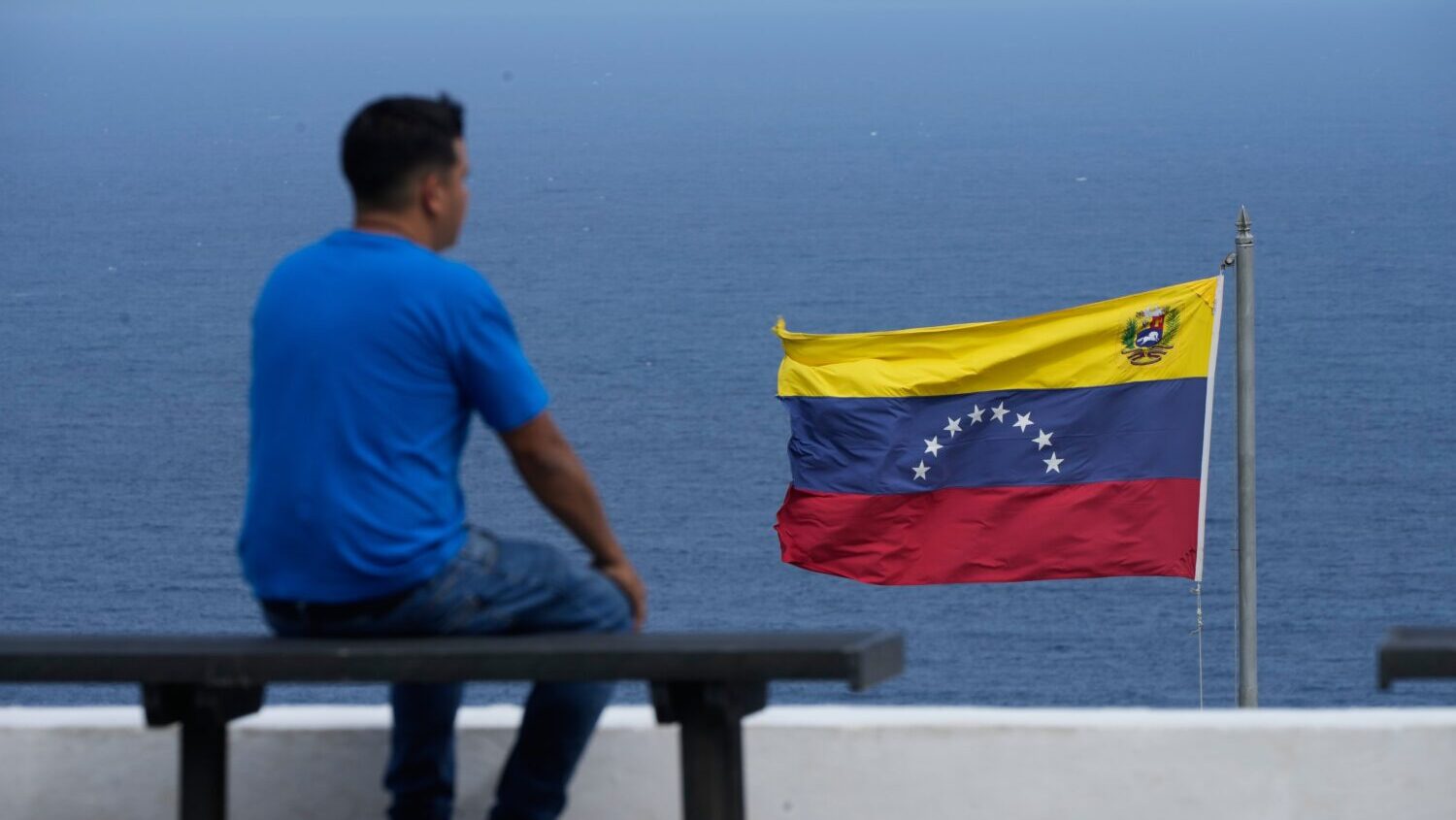 A man looks out at the sea in the city of La Guaira, Venezuela, where the nation's flag flies, Wedn...
