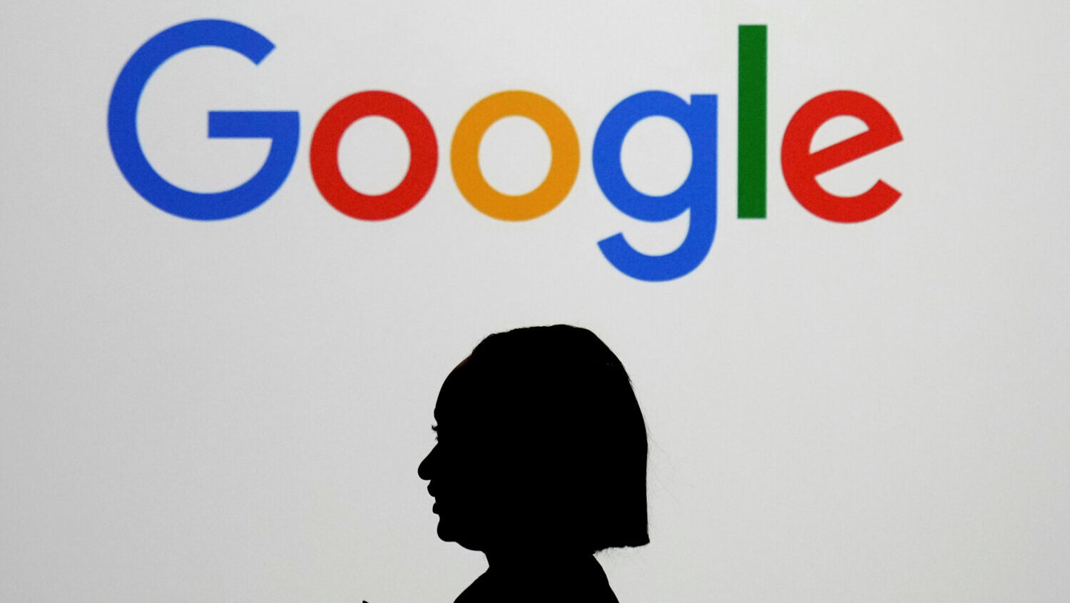 A woman walks by a giant screen with a logo at an event at the Paris Google Lab on the sidelines of...