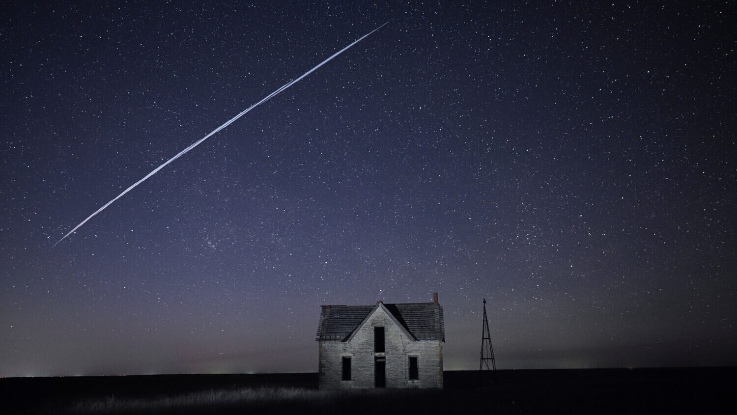 FILE - In this long exposure photo, a string of SpaceX StarLink satellites passes over an old stone...
