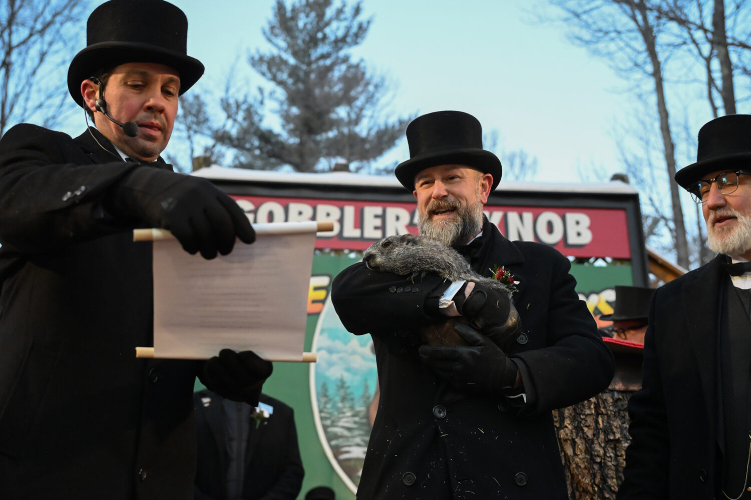 Groundhog Club Vice President Dan McGinley reads the scroll as handler A.J. Dereume holds Punxsutaw...